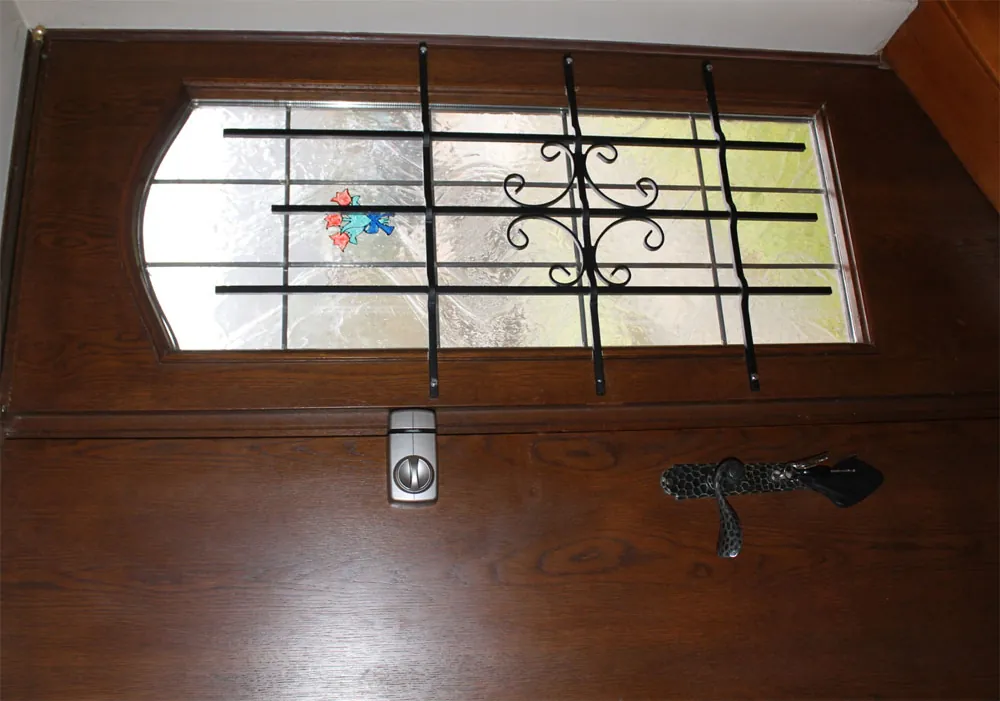 Haustür mit Glasfeld und schwarzem schmiedeeisernem Gitter