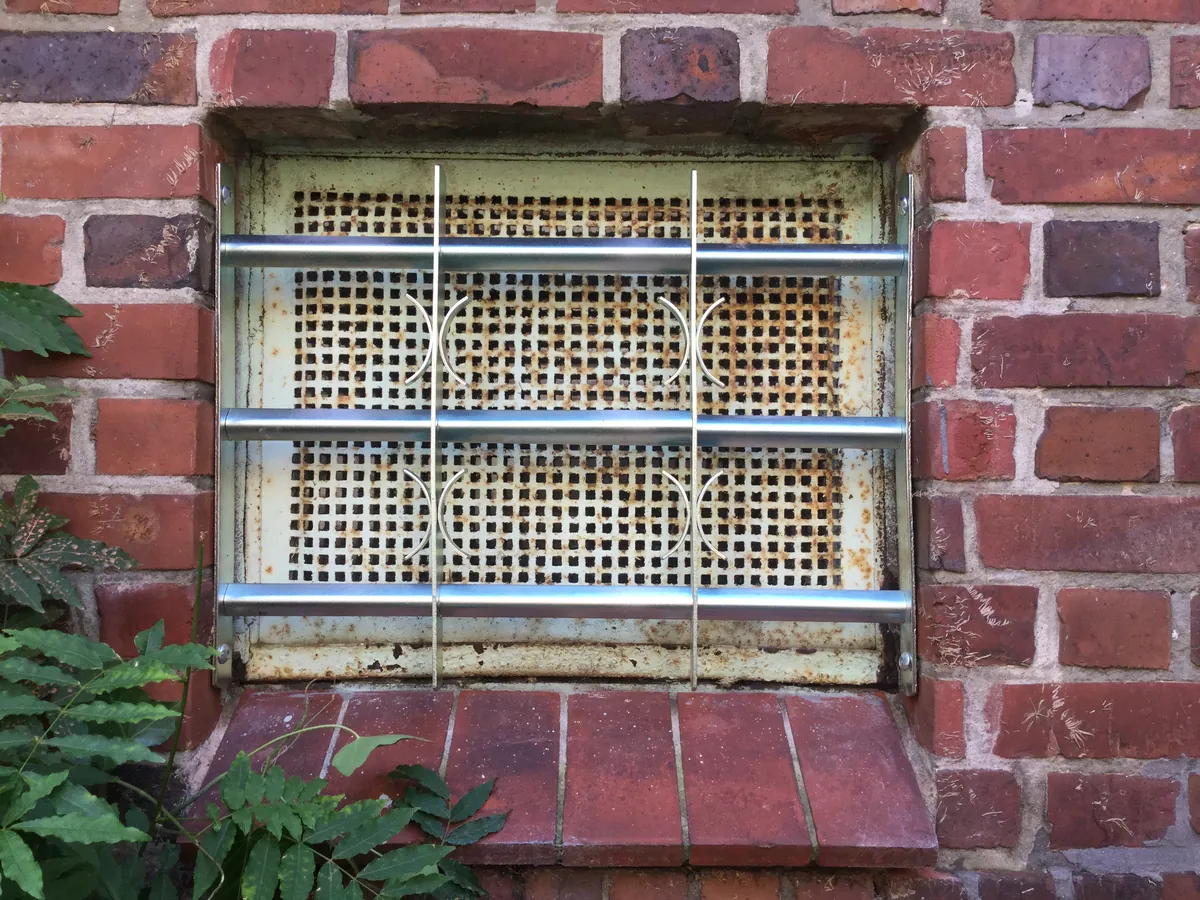 Kellerfenster in Backsteinwand mit Stahlgitter