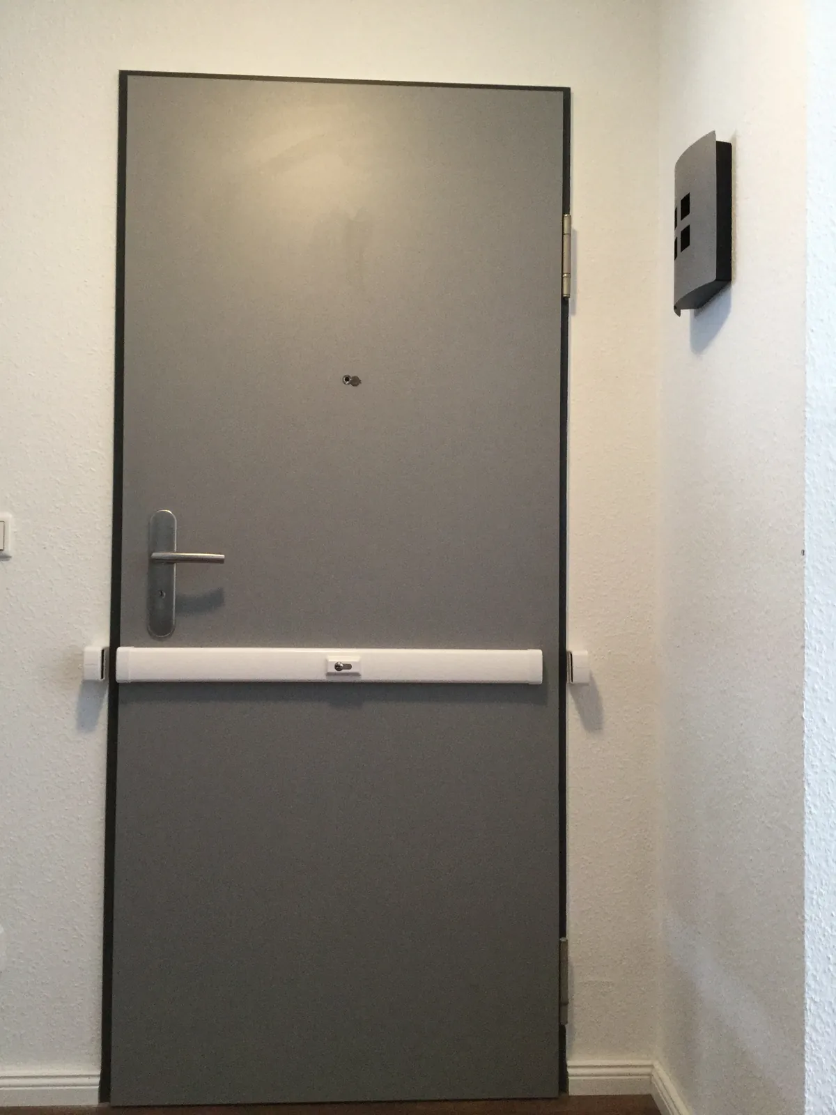 Graue Wohnungstür mit weißem Panzerriegel