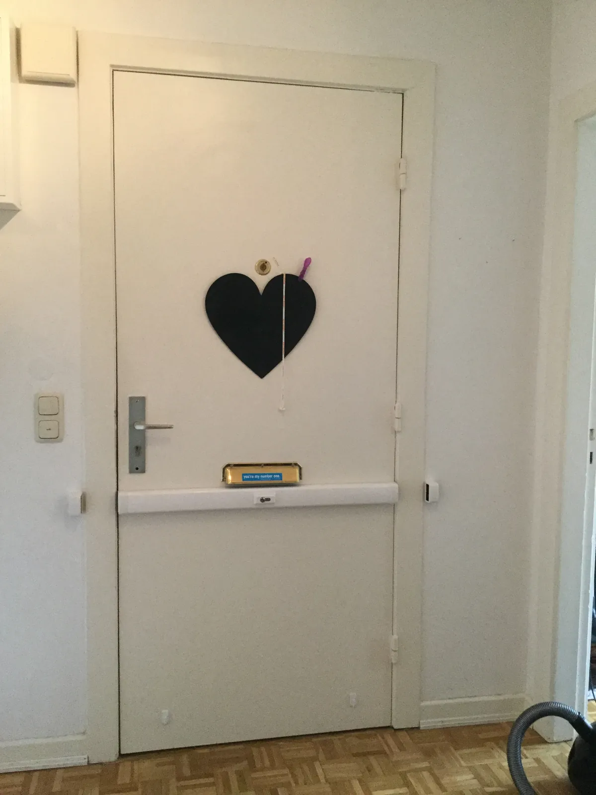 Weiße Wohnungstür mit Herz und Panzerriegel
