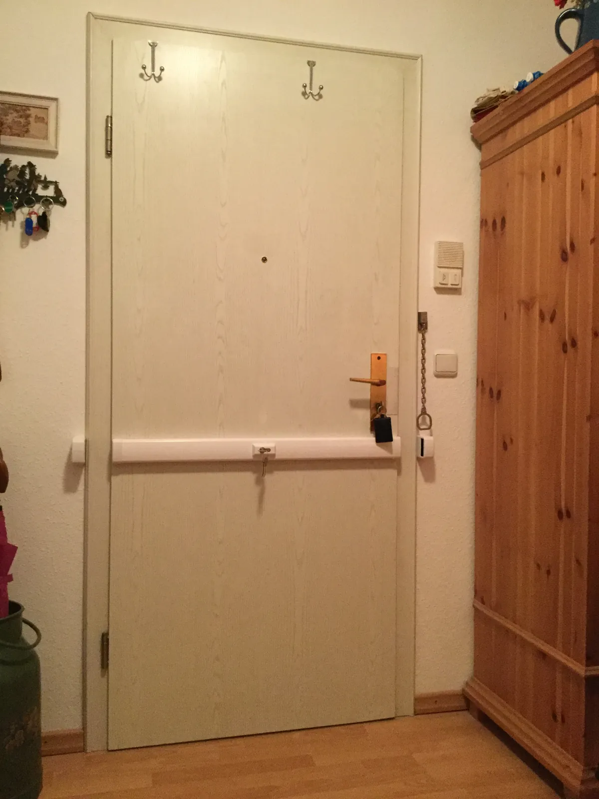 Holzfarbene Wohnungstür mit Panzerriegel neben einem Schrank